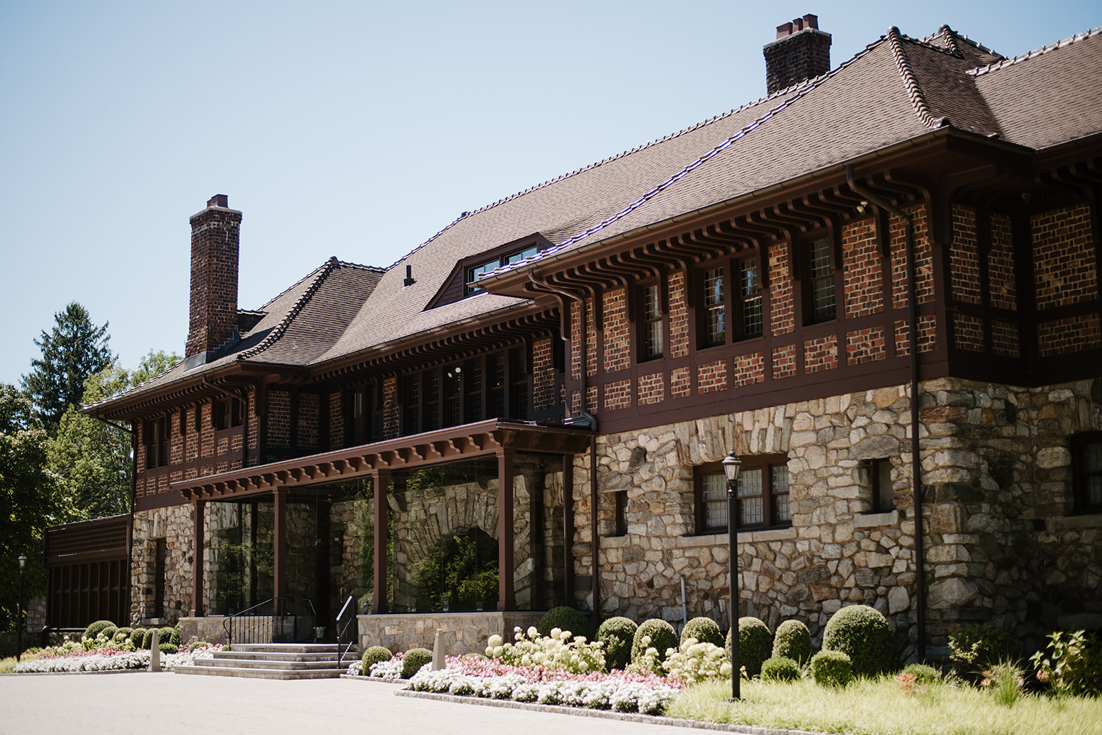 Grand stone and brick facade of Le Chateau mansion standing under a clear blue sky.